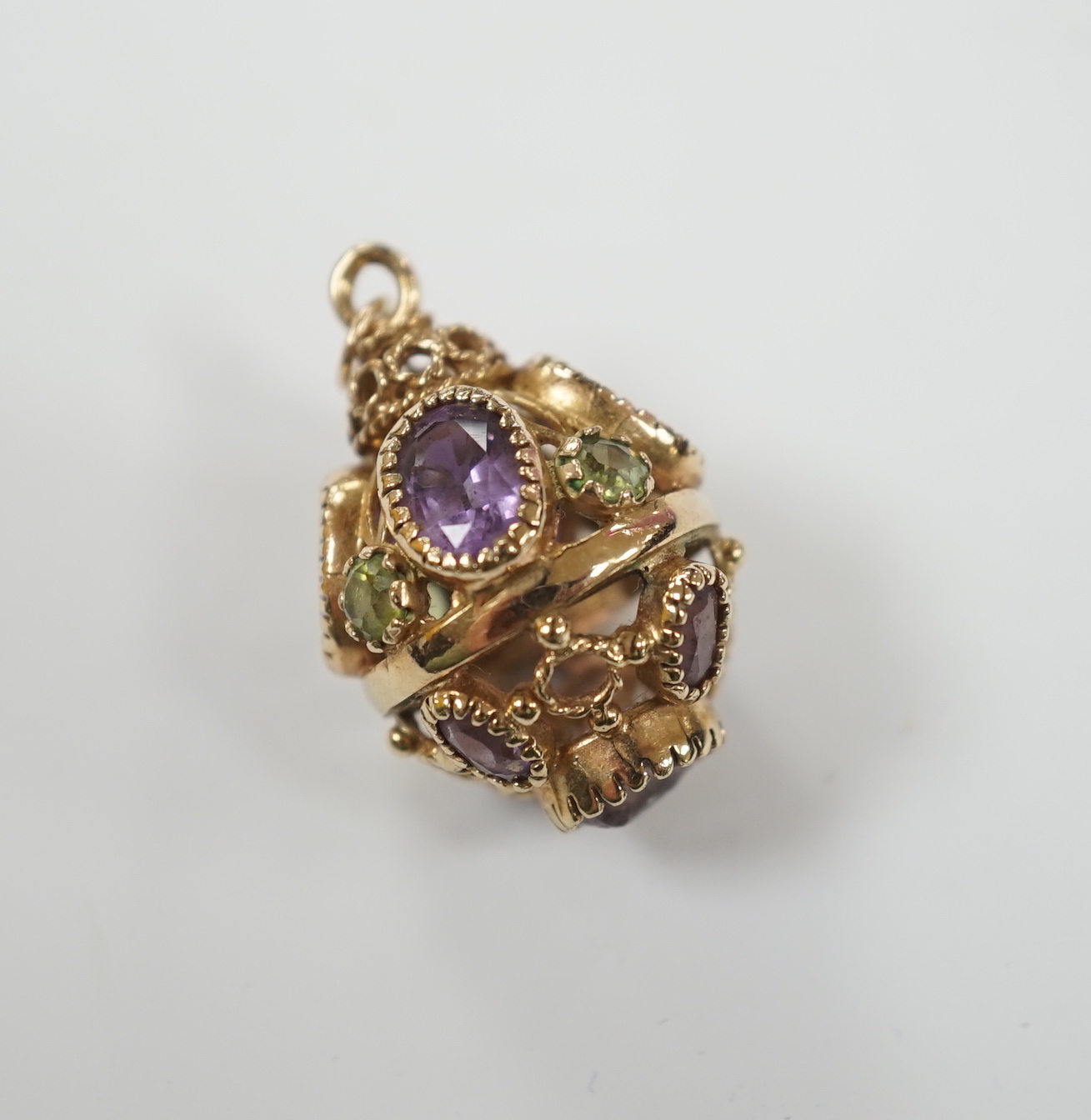 A modern 9ct gold, amethyst and peridot set pendant, or pierced spherical form, 25mm, gross weight 7.5 grams.